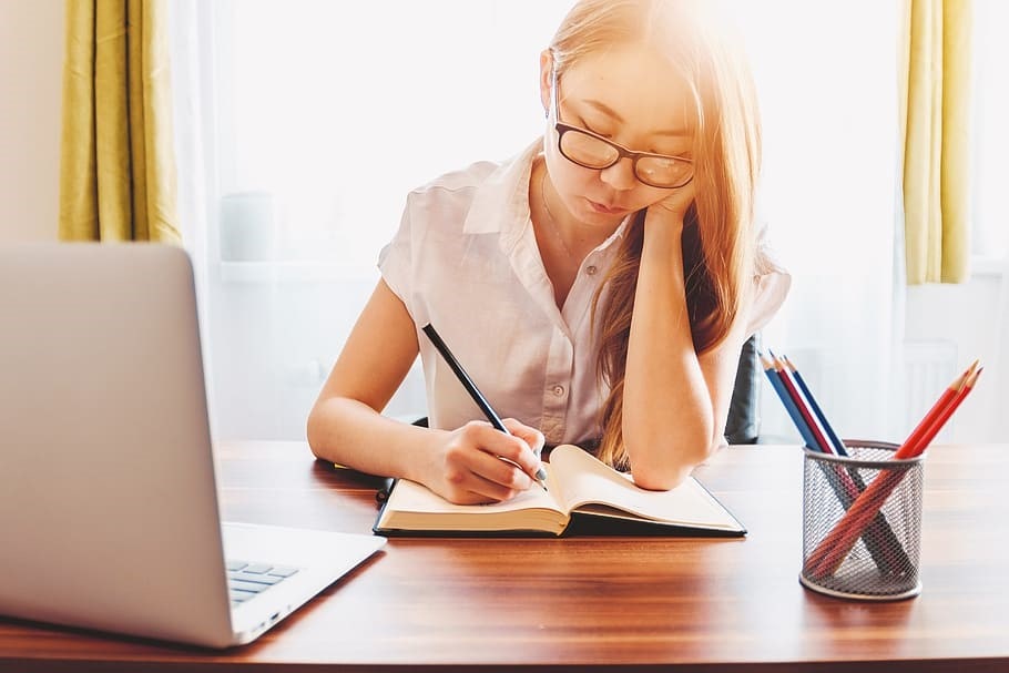 Girl with glasses writing down in notebook 