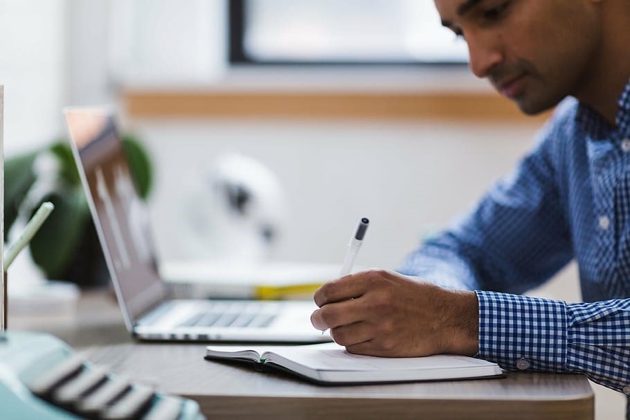 Man on desk writing for research purposes